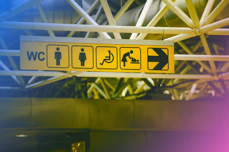 an accessibility sign in a subway station with icons for men, women, the disabled, mothers, and more with a blue and pink gradient overlaid on top.